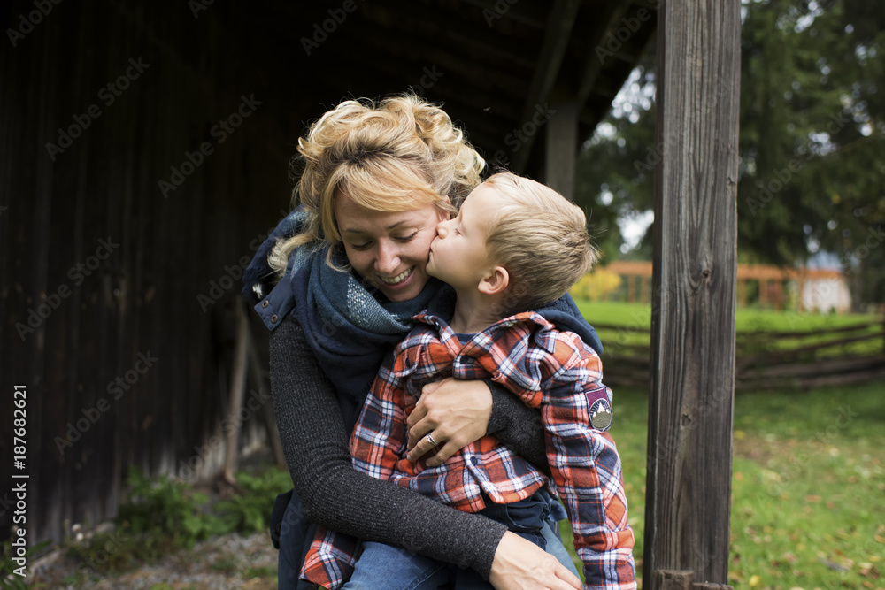 Son kissing smiling mother at farm Son kissing smiling mother at farm