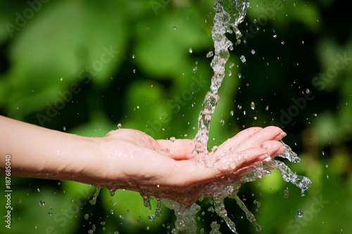 Woman washing hand outdoors. Natural drinking water in the palm. Young hands with water splash, selective focus