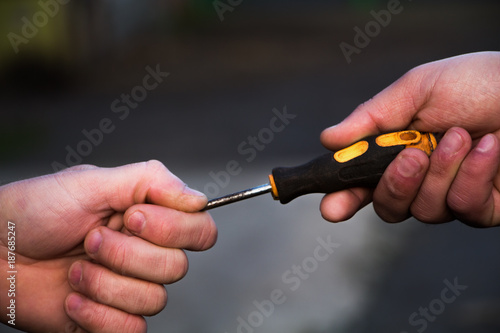 a man passes a screwdriver to another man