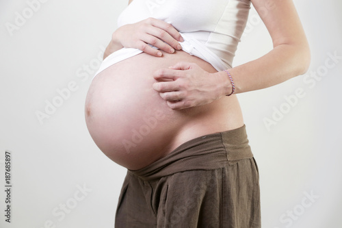Pregnant woman scratches her belly