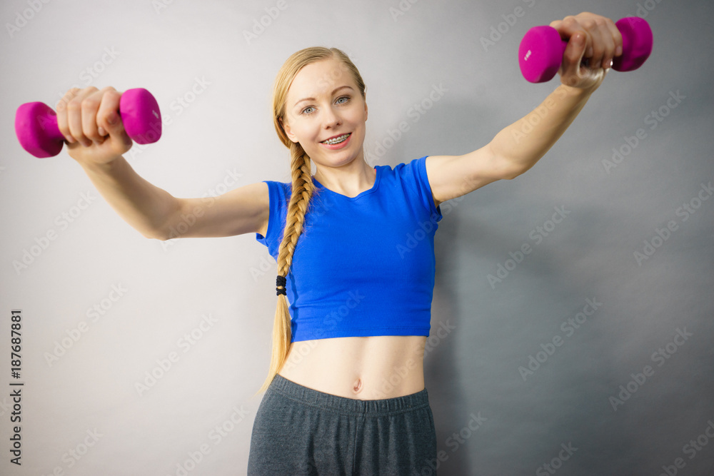 Teenage woman working out at home with dumbbell Teenage woman working out at home with dumbbell