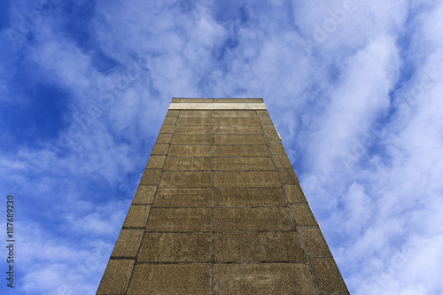The wall of a multi-storey house shot on a wide-angle lens, creates the impression of a springboard into the blue sky.
