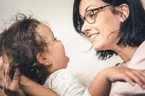 Happy mother talking to her small daughter.