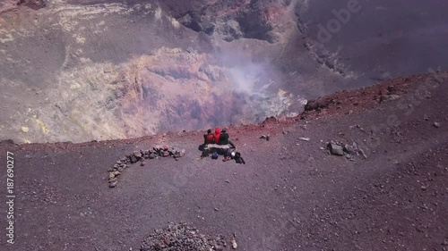 sitting crater steamMountaineers seated on the edge and looking to the smoked crater. Beautiful horizon of mountains. Aerial view of mountaineers contemplating an active crater. 4k aerial 4k photo