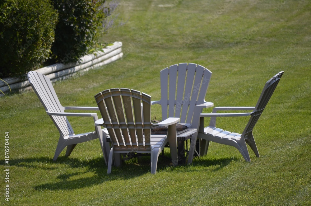 Four chairs gathered around a fire pit in the backyard for social time with friends and neighbors Four chairs gathered around a fire pit in the backyard for social time with friends and neighbors