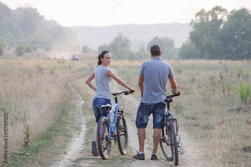 Happy young couple with bicycles in countryside.