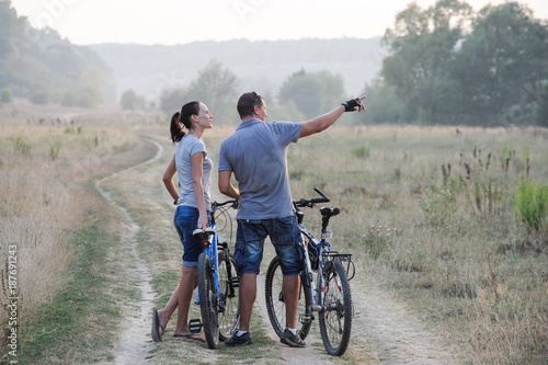 Happy young couple with bicycles in countryside.