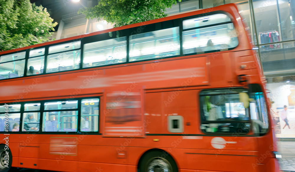 Red bus speeding up along city streets, London, UK