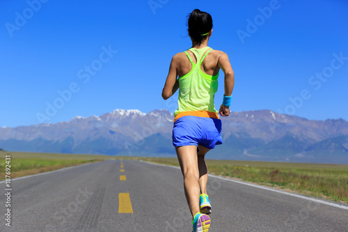 Young fitness healthy lifestyle woman runner running on road with snow capped mountains in the distance