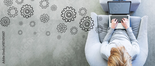 Gears with man using a laptop in a modern gray chair