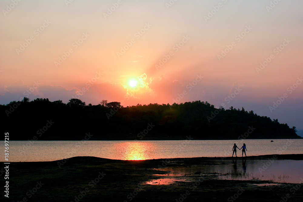 Landscape of Natural view in sunset. Silhouette of Two Traveler on the beach with mountain view near sunset or sunrise time. Travel Concept. Landscape of Natural view in sunset. Silhouette of Two Traveler on the beach with mountain view near sunset or sunrise time. Travel Concept.
