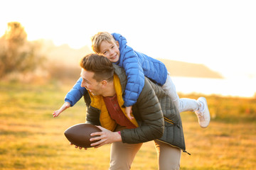 Father with little son playing rugby outdoors