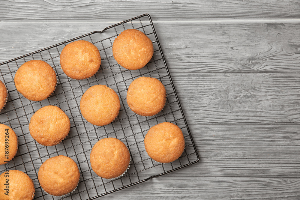 Cooling rack with delicious cupcakes on wooden background, top view Cooling rack with delicious cupcakes on wooden background, top view