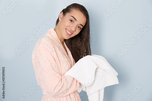 Young woman drying her hair with towel on light background