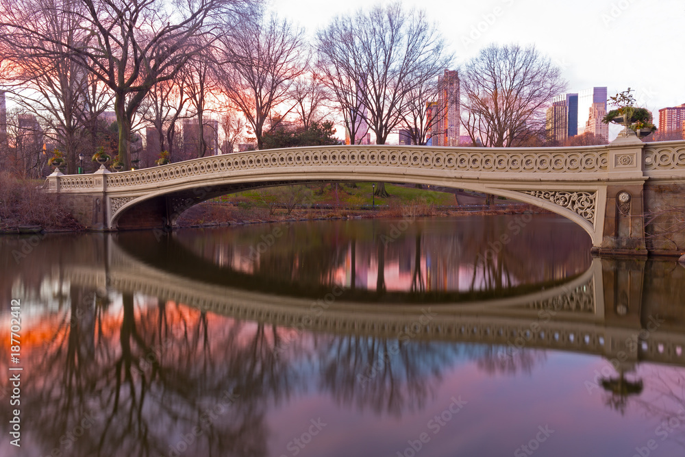 Fototapeta Łęku most przy pięknym zima wschodem słońca w central park, Miasto Nowy Jork. Największy most parkowy z odbiciem ozdobiony sadzeniem urn.