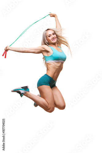 Full length image of a young sports woman jumping on skipping rope over white background