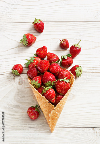 Strawberry explosion. Photo of strawberry in waffle cone on white wooden table. Top view. High resolution product.