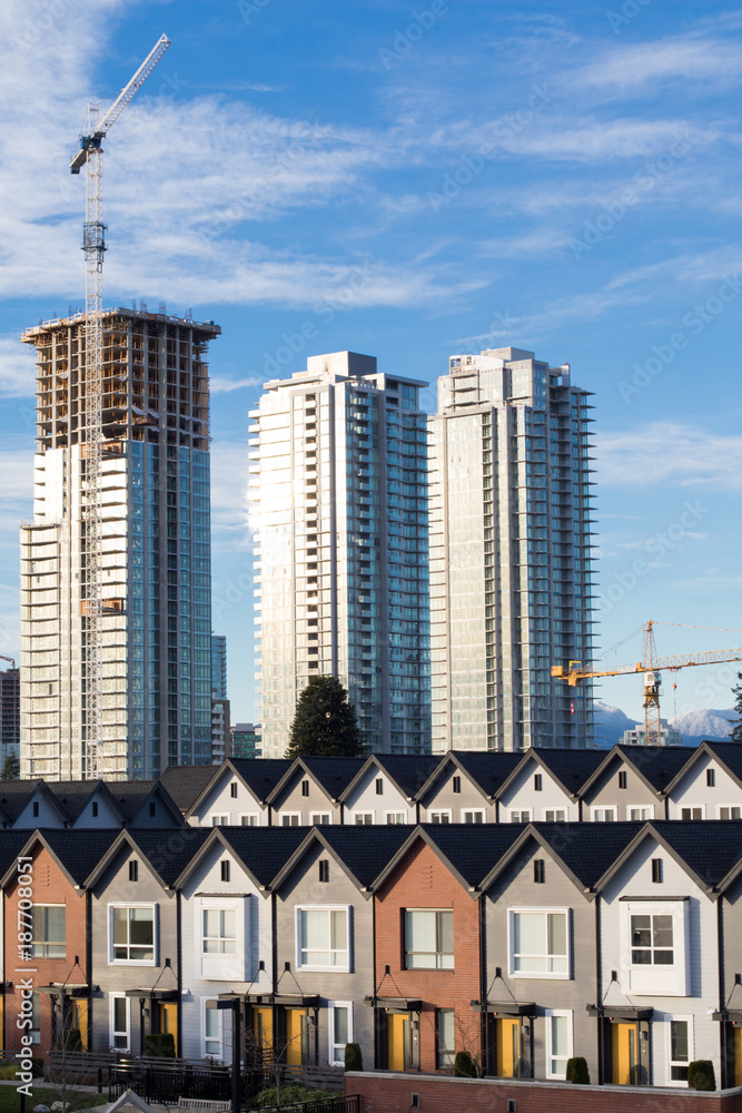 Fototapeta premium Brand new townhouses in a row on bright sunny day with Highrises in the background.