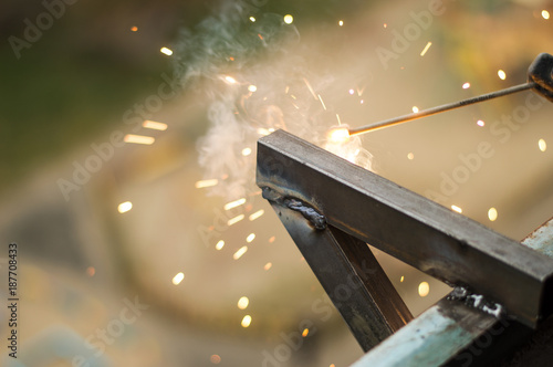 A man welds a triangular iron structure on the balcony of a residential building