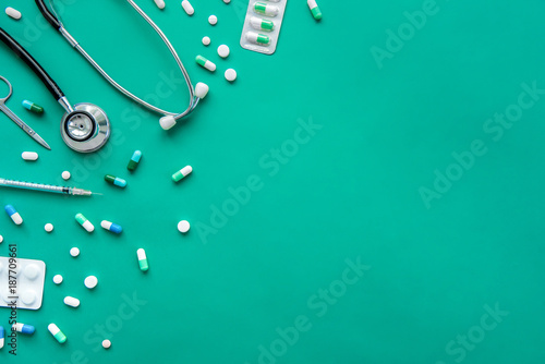 Pills and medical equiupments at border on green background, top view photo