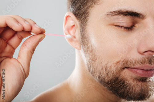 Close up portrait of a young man cleaning his ears