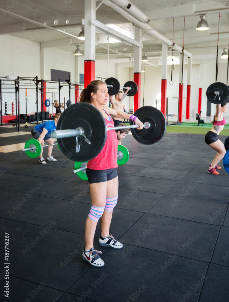 Determined Woman Lifting Barbell In Gym