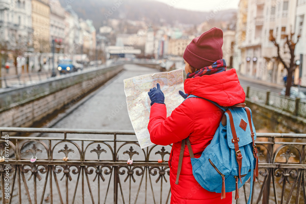 A happy woman on the bank of the Tepla river in Karlovy Vary looking at a map and tries to find a tourist attraction A happy woman on the bank of the Tepla river in Karlovy Vary looking at a map and tries to find a tourist attraction