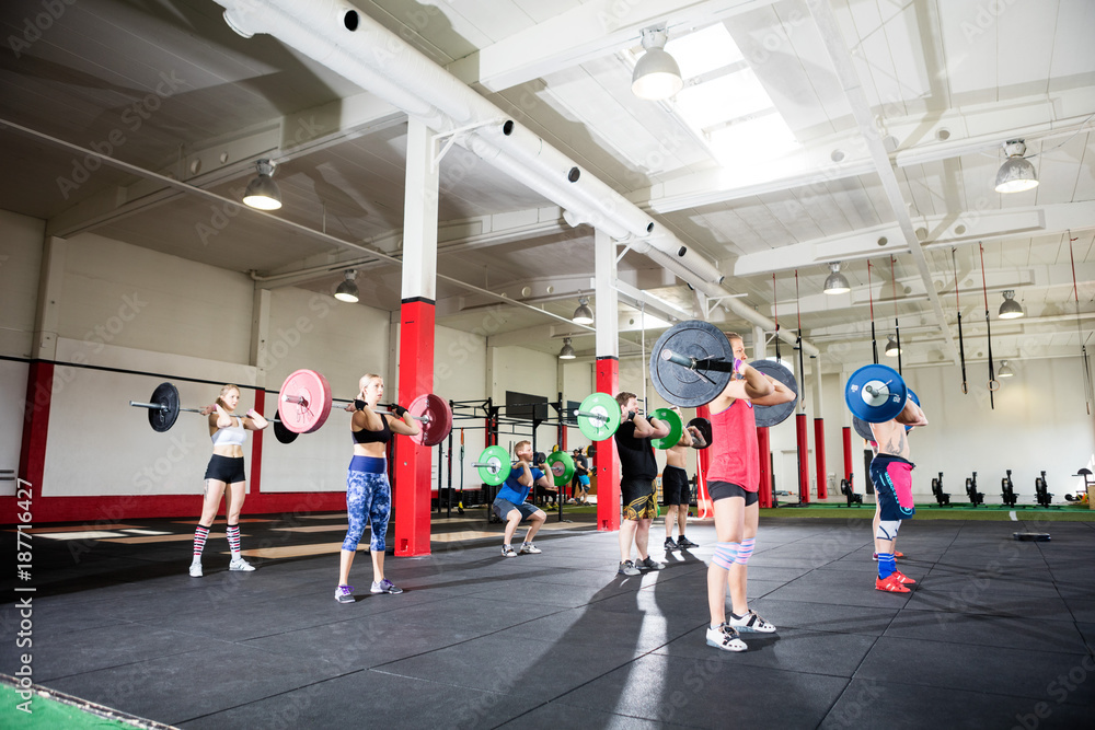 Obraz premium Male And Female Friends Lifting Barbells