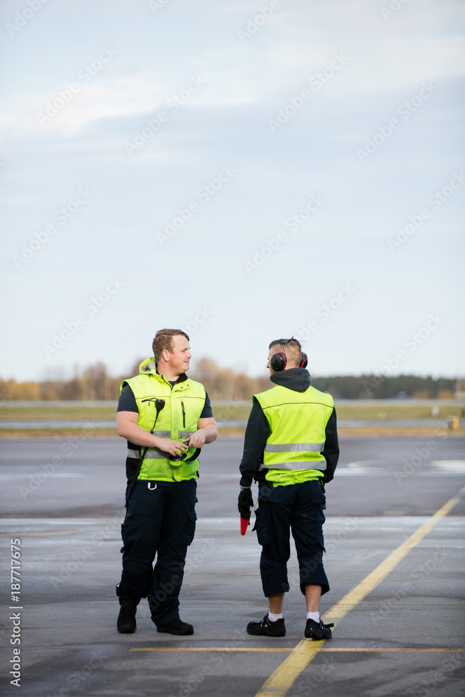 Fototapeta premium Workers In Reflective Jackets Standing On Airport Runway