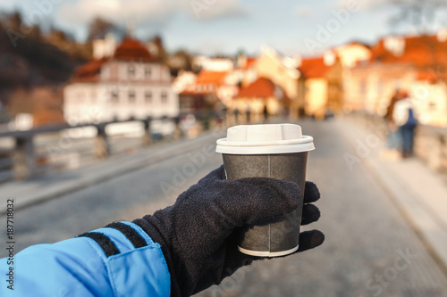 Photography The hand holds a hot drink in a takeaway mug against the background of the old E