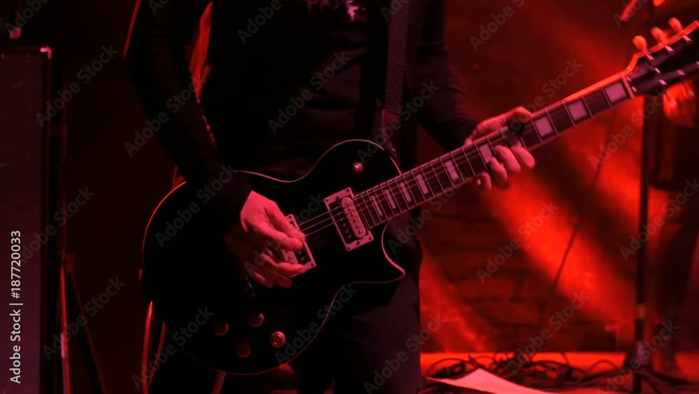 Close up shot of man playing guitar on concert stage. Smoke, red light. Entertainment and art concept Close up shot of man playing guitar on concert stage. Smoke, red light. Entertainment and art concept