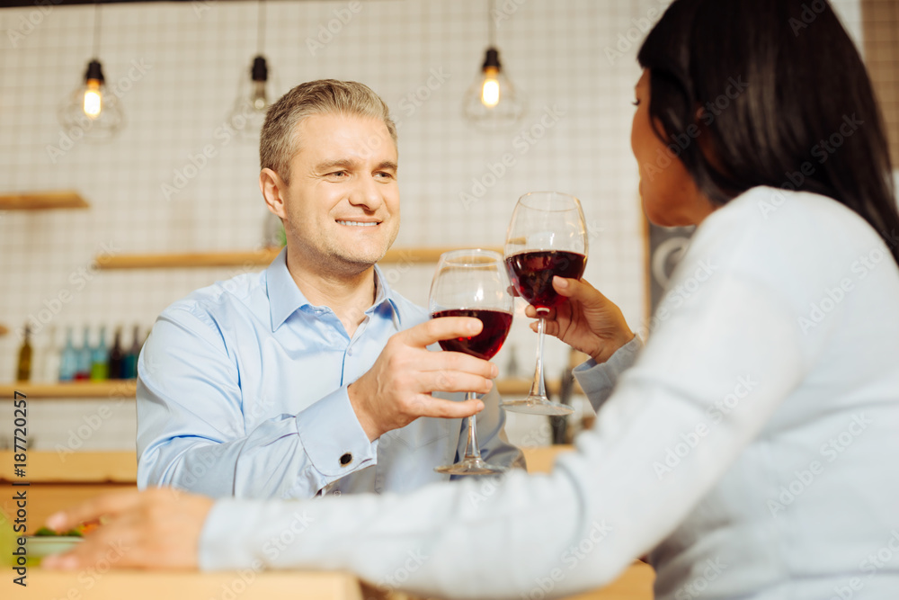 Delicious wine. Handsome exuberant well-built man and a dark-haired woman sitting together and drinking wine and having dinner Delicious wine. Handsome exuberant well-built man and a dark-haired woman sitting together and drinking wine and having dinner