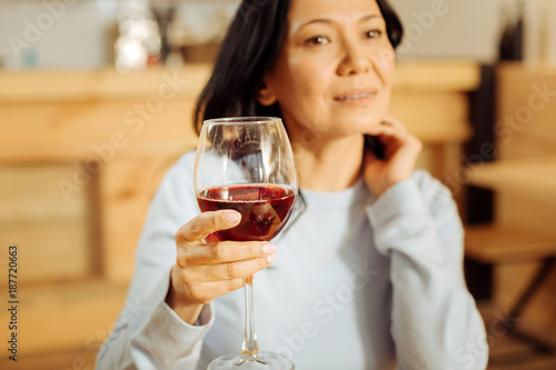 Thinking. Attractive thoughtful dark-eyed woman thinking and looking in the distance while drinking red wine