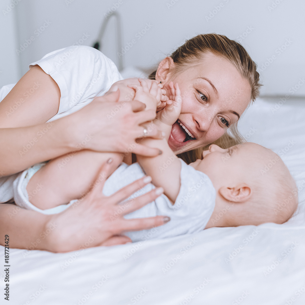 happy mother playing with her infant baby in bed happy mother playing with her infant baby in bed