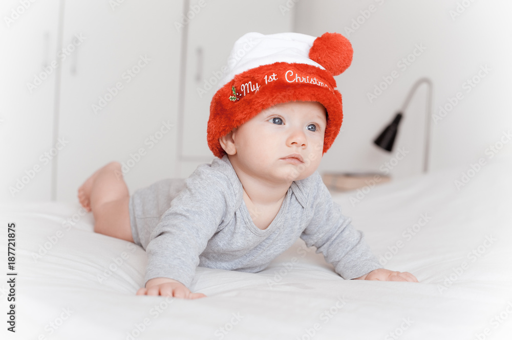 portrait of beautiful little infant child in santa hat lying on bed portrait of beautiful little infant child in santa hat lying on bed