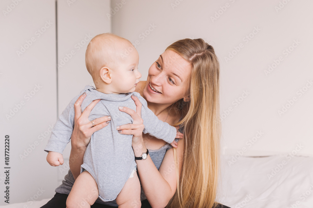 beautiful young mother hugging and lookign at adorable infant child beautiful young mother hugging and lookign at adorable infant child
