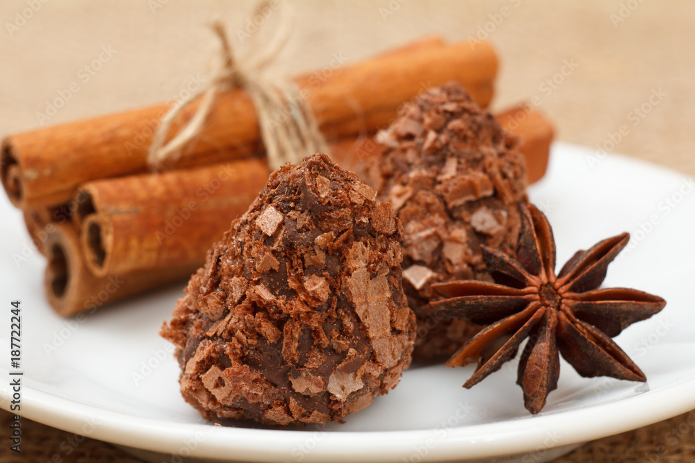 Chocolate candy truffles on white plate with star anise and cinnamon Chocolate candy truffles on white plate with star anise and cinnamon