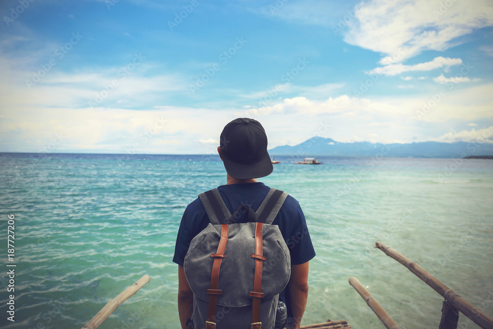 Εκτύπωση καμβά Back of male backpacker standing at the edge of coastline beach enjoying leisure time