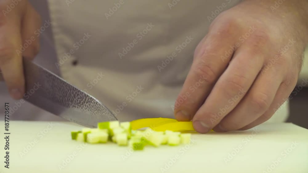 Cooking in the restaurant. Close up hands of chef cutting up a paprika with a knife Cooking in the restaurant. Close up hands of chef cutting up a paprika with a knife