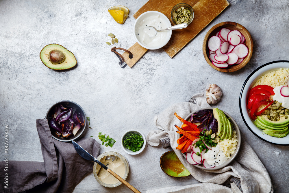 Fototapeta premium Fresh healthy vegetarian bowl for lunch with baked carrots and red onion, coucous and sliced avocado. Simple and colourful organic food concept. Flat lay with copy space.