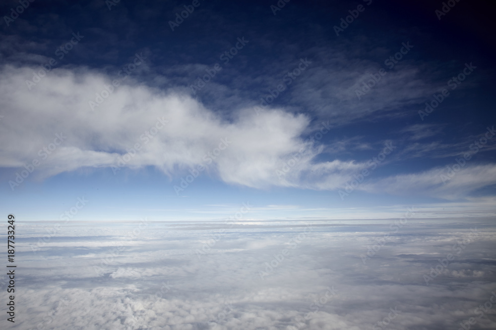 Obraz premium flying high in a blue sky with white clouds and sun shine