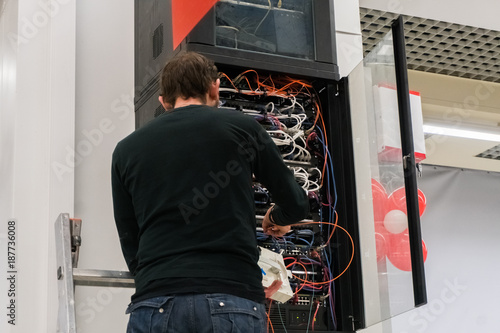 Young engeneer man in network server room connecting wires