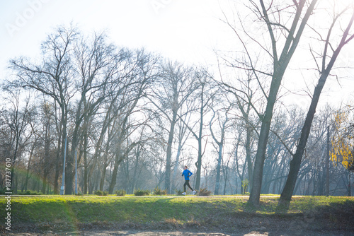 Young Sports Man Running in the Park in Cold Sunny Autumn Morning. Healthy Lifestyle and Sport Concept.