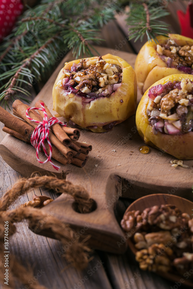 Baked apples stuffed with berries, walnuts and honey on a wooden cutting board.