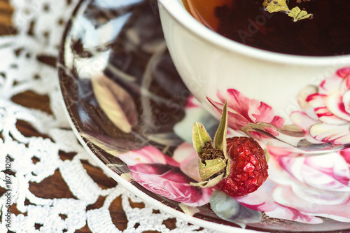 Tea rosehip. Vitamin herbal drink. Cup of fruit rose hip tea and dried fruits of wild rose on table close-up detail. Medicinal tea from the berries of the autumn dogrose. Selective focus.