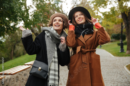 Two happy girls dressed in autumn clothes walking