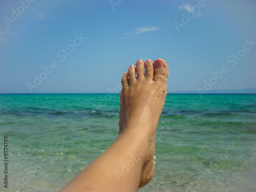 female feet with sand and turquoise water background © Florin