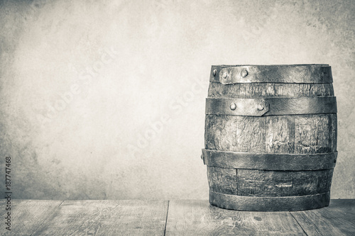 Fényképezés Classic old retro aged oak barrel with hoops on wooden floor front concrete wall background