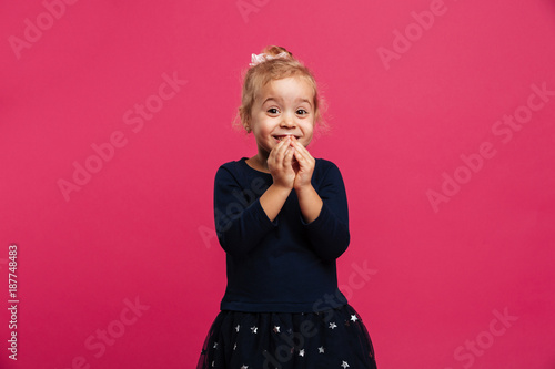Cheerful young blonde girl holding arms together near her face