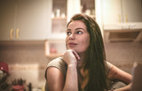 Portrait of young woman sitting in kitchen.